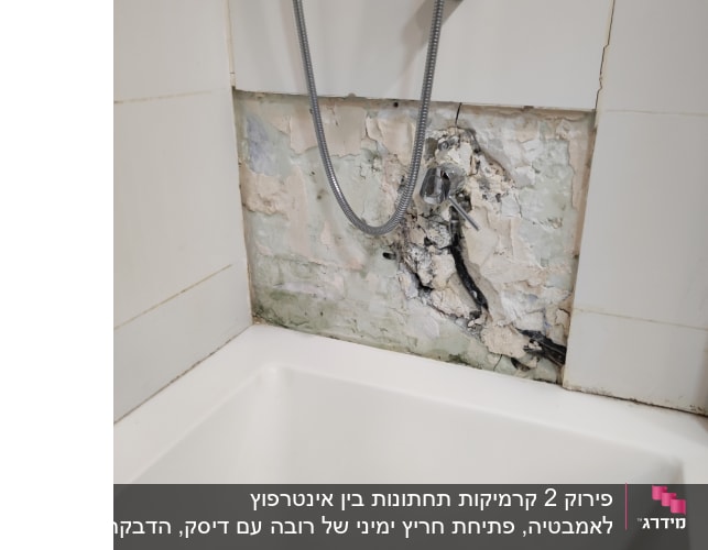 קיר אמבטיה עם אריחים שבורים וצינור מים חשוף